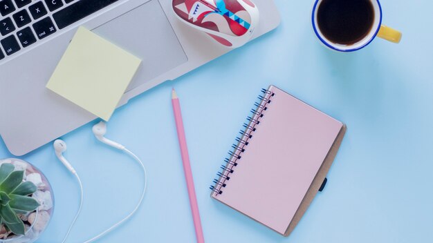 Earphones and stationery near coffee and laptop