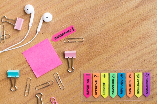 Earphones with stationery located on wooden table