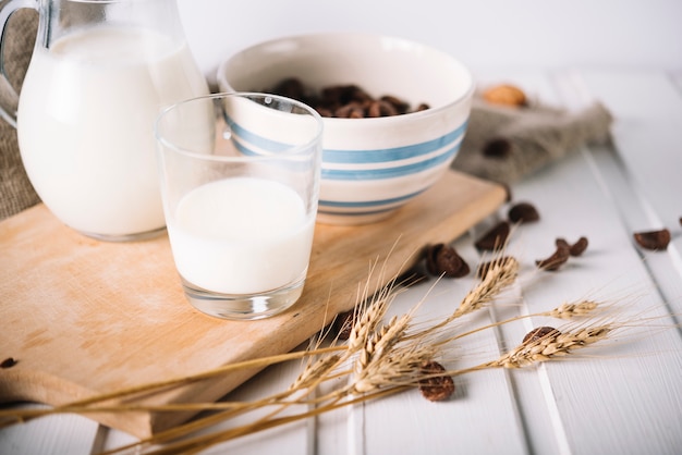 Ears of wheat with milk glass and cereals on table