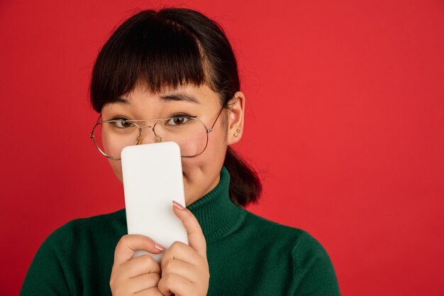 East asian young beautiful woman's portrait on red background with copyspace.