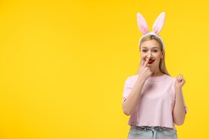 Free photo easter adorable pretty young blonde girl with bunny ears pranking and touching tip of her nose