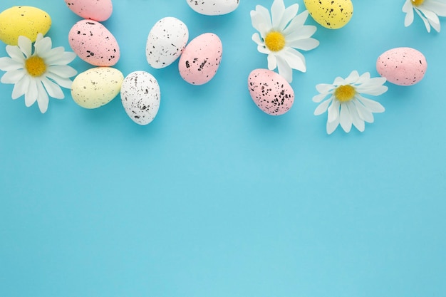 Easter background with eggs and daisies on a blue background with copy space