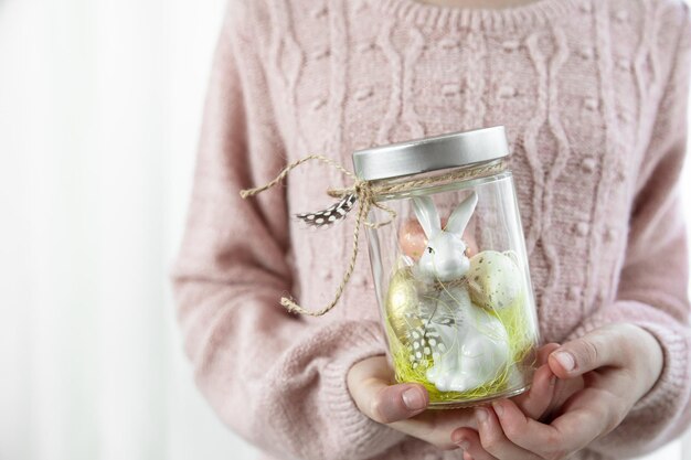 Easter background with a jar with a festive decor in childrens hands