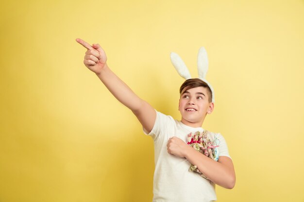 Easter bunny boy with bright emotions on yellow studio wall
