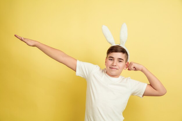 Easter bunny boy with bright emotions on yellow  wall