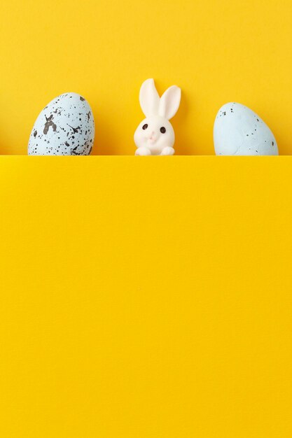 Пасхальный кролик с яйцами на желтом фоне с копией пространства