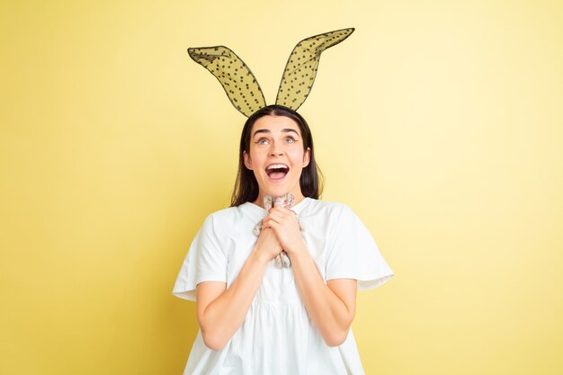 Easter bunny woman with bright emotions on yellow studio