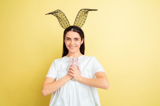 Easter bunny woman with bright emotions on yellow  wall