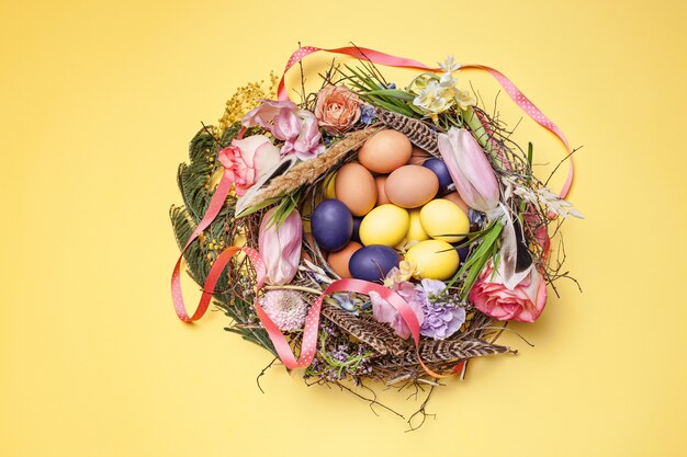 Easter card. Painted Easter eggs in nest on yellow