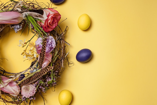 Foto gratuita carta di pasqua. uova di pasqua dipinte in nido su giallo