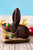 Foto gratuita coniglietto di cioccolato di pasqua e uova colorate sulla tavola di legno