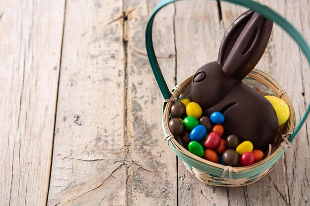 Пасхальный шоколадный кролик и разноцветные яйца на деревянном столе