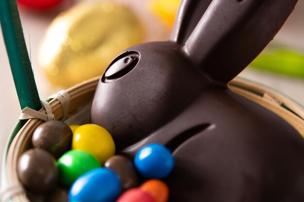 Пасхальный шоколадный кролик и разноцветные яйца на деревянном столе