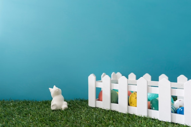 Easter composition of rabbit close to a wooden fence with colored eggs