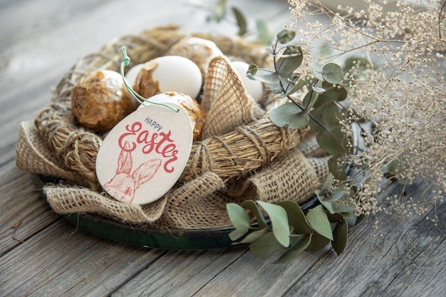 Пасхальная композиция с украшенными пасхальными яйцами и декоративным гнездом на деревянной поверхности