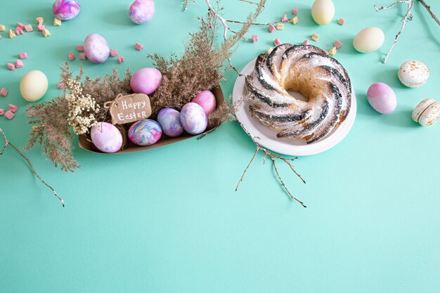 Easter composition with eggs and cupcake on a colored background.