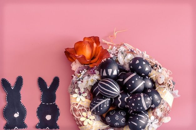Easter composition with eggs and the Easter Bunny on a pink table