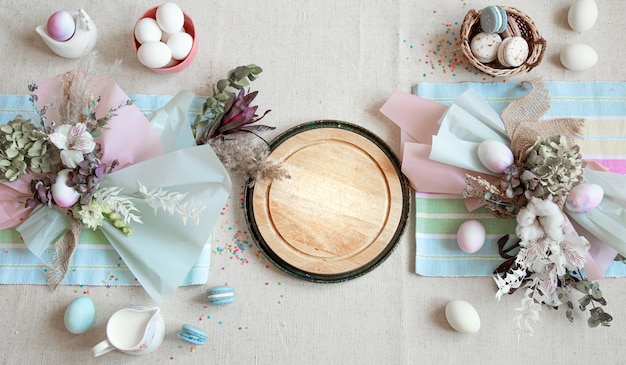 Easter composition with flowers, eggs and wooden space for text in pastel colors flat lay.