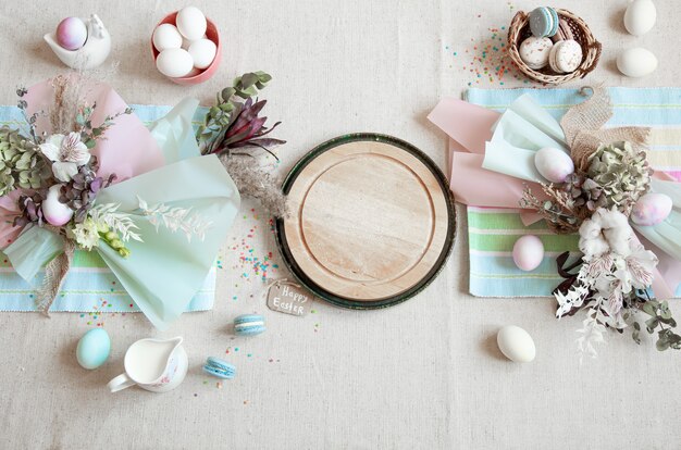 Easter composition with flowers, eggs and wooden space for text in pastel colors flat lay.