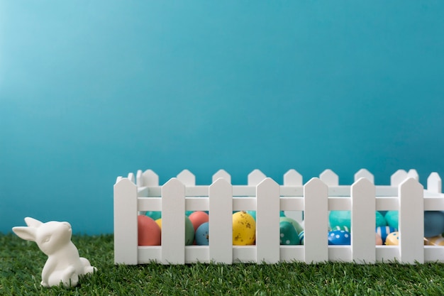 Easter composition with rabbit, fence and colored eggs
