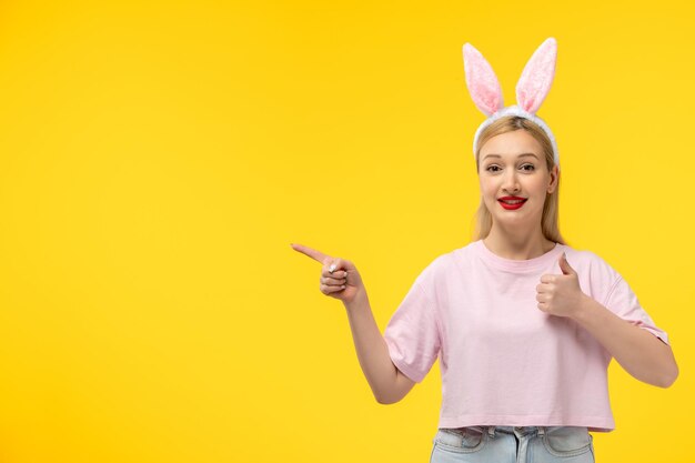 Easter cute young blonde girl wearing pink bunny ears showing good sign gesture and smiling