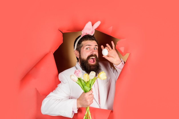 День пасхи счастливый бородатый мужчина держит пасхальное яйцо и цветы весенний праздник костюм пасхального кролика весна