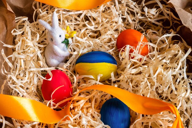 Easter egg decorated in the ukrainian flag colors in the center of the basket with an Easter rabbit