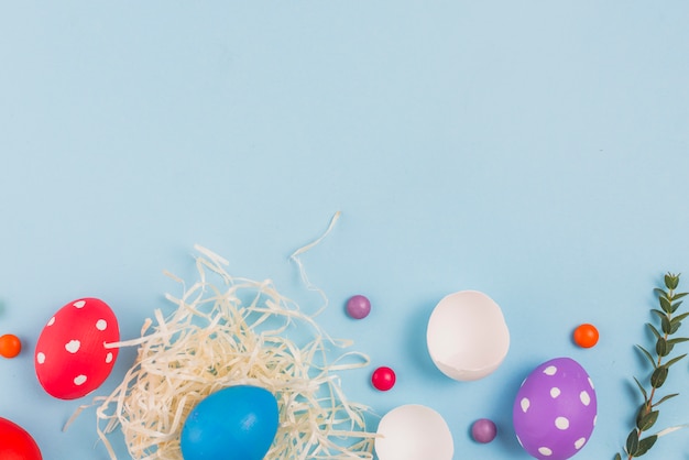 Easter egg in nest with green plant branch and candies 