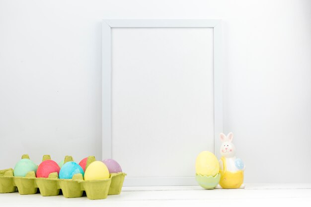 Easter eggs in box with blank frame on table