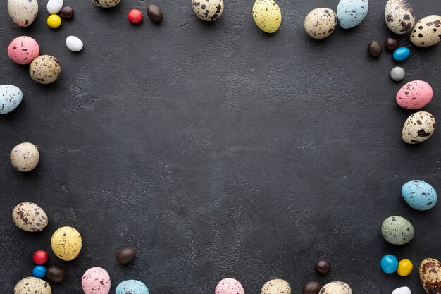Easter eggs frame with candy on slate background