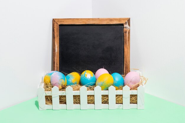 Easter eggs on hay in box with chalkboard 