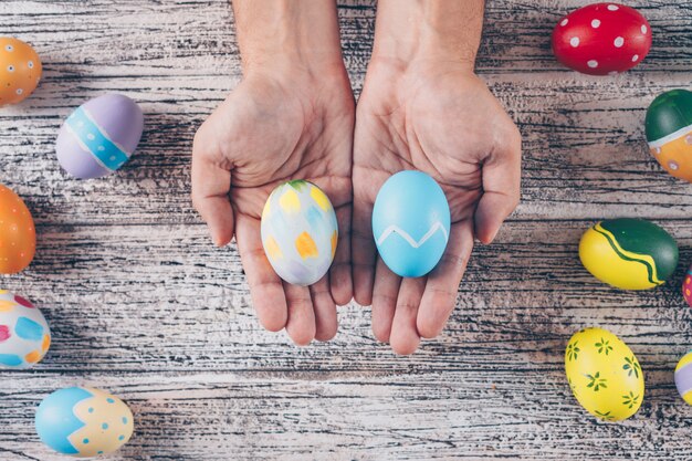 Easter eggs in man_s hands and on wooden background.