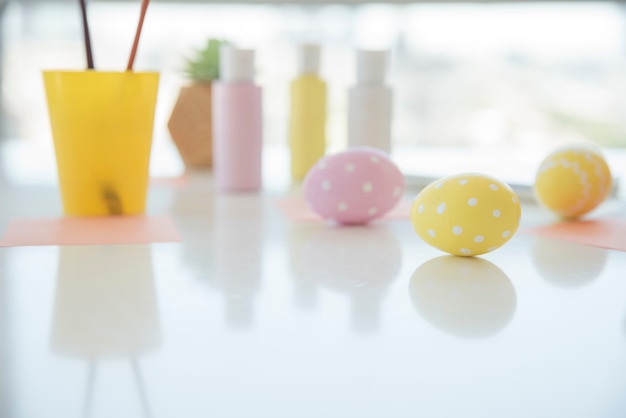 Easter eggs near sheets and colors on table