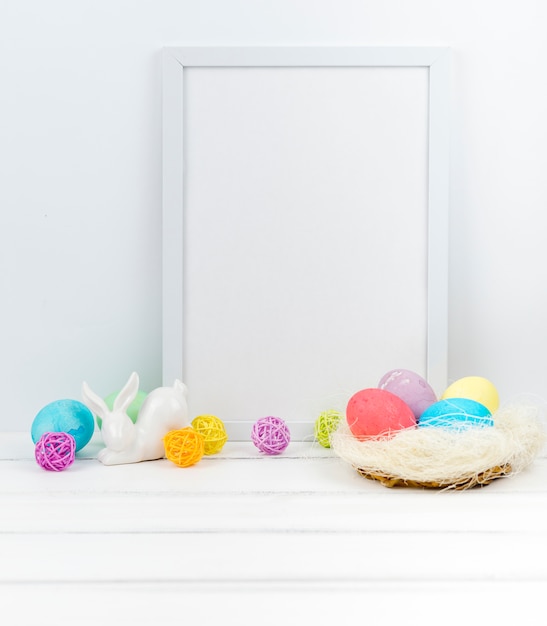 Free photo easter eggs in nest with blank frame on table