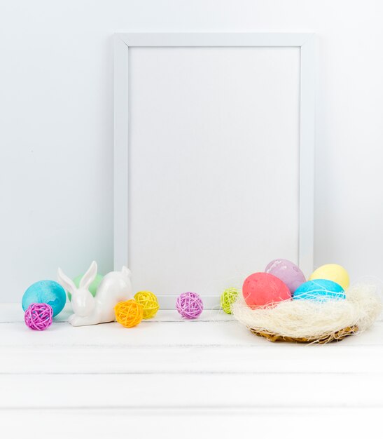 Easter eggs in nest with blank frame on table 