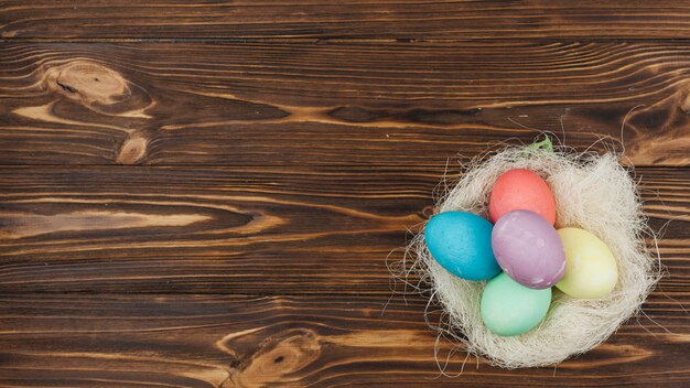 Easter eggs in nest on wooden table