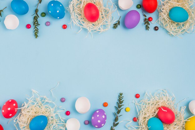 Easter eggs in nests with plant branches and candies 