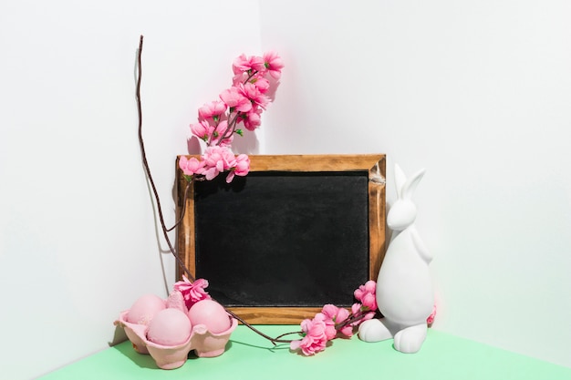 Easter eggs in rack with chalkboard and flowers on table