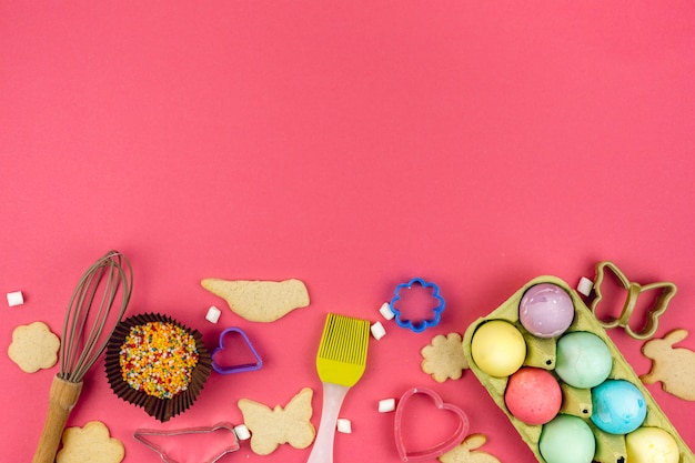 Foto gratuita uova di pasqua in rack con biscotti e utensili da cucina