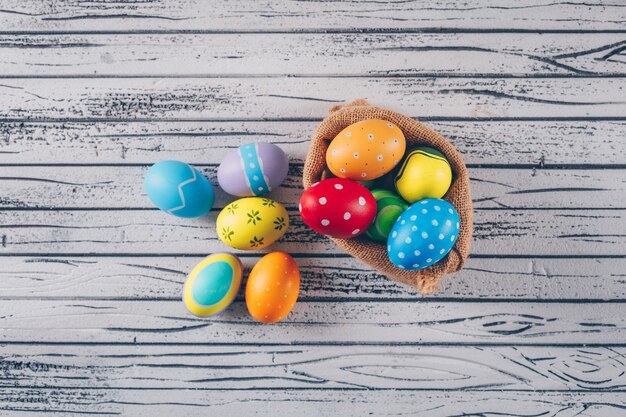 Easter eggs in sack on light wooden background.