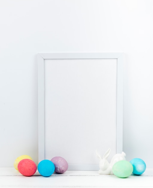 Easter eggs with blank frame on table 