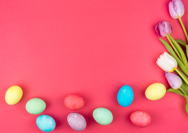 Easter eggs with bright tulips on red table