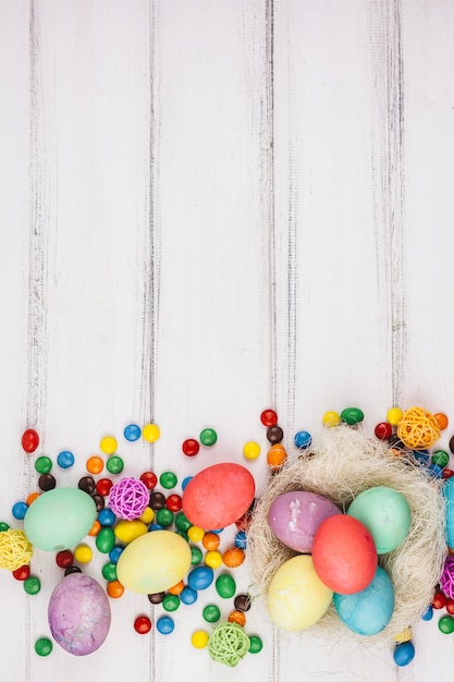 Foto gratuita uova di pasqua con piccole caramelle sul tavolo