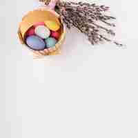 Free photo easter eggs in wooden basket with willow branches