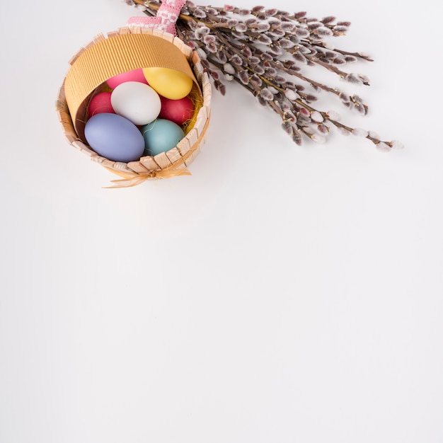 Easter eggs in wooden basket with willow branches 