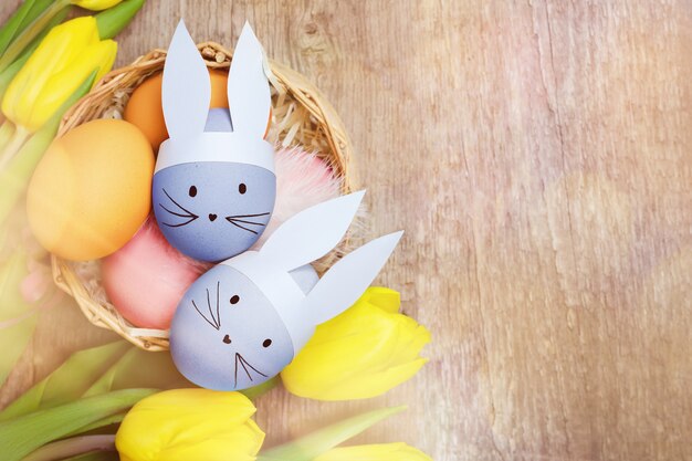 Easter eggs and yellow tulips on wooden background