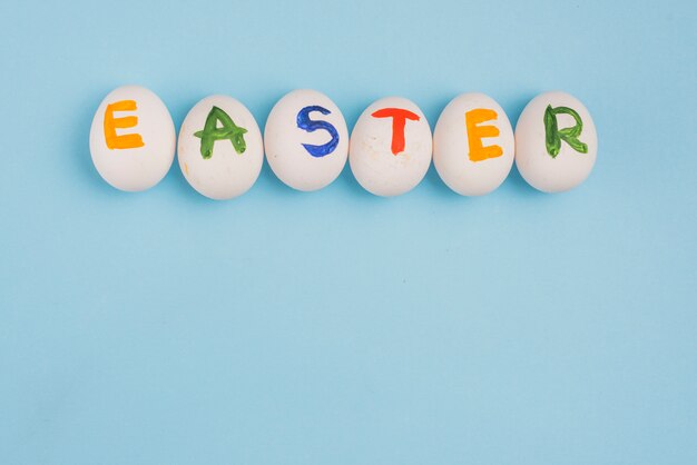 Easter inscription on eggs on blue table