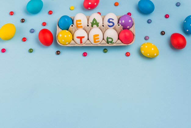 Free photo easter inscription on eggs in rack on blue table