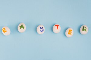 Бесплатное фото Пасхальная надпись на белые яйца на синем столе