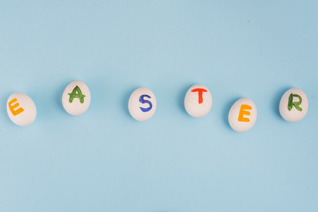 Easter inscription on white eggs on blue table